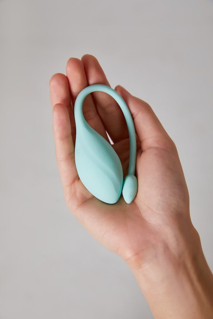 a hand holding a small blue object in it's palm