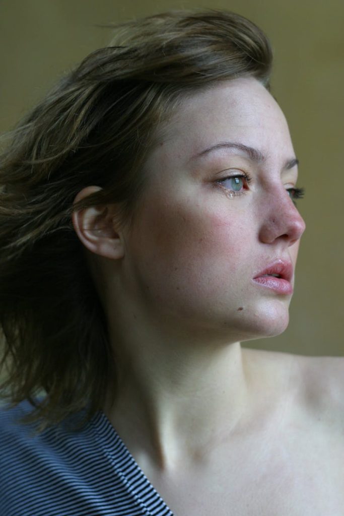 A young woman looks thoughtfully into the distance, capturing emotions with a side profile view. Violencia machista.