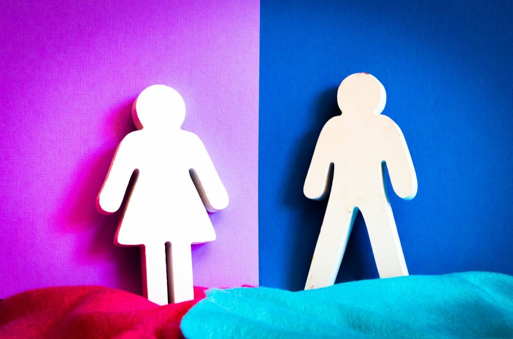 Cutout figures of a man and woman on vibrant purple and blue backgrounds. Género